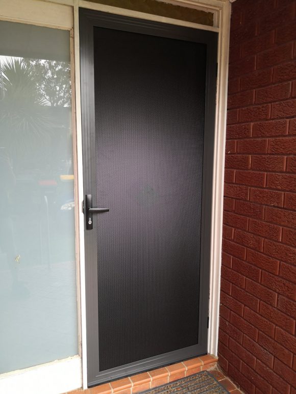 Charcoal security screen door installed at a brick home