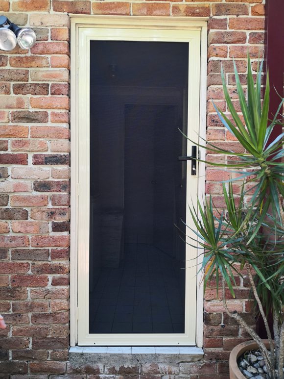 Cream security screen door on a brick house entrance